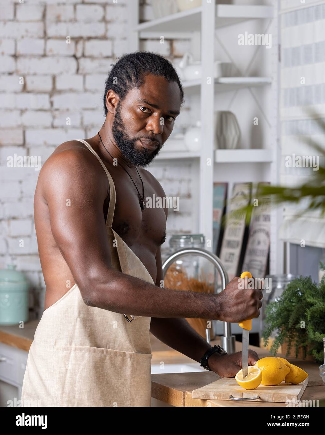 Hombre negro cocinando el desayuno o el almuerzo en la cocina en casa.  Hombre afroamericano usando un delantal preparando limón Fotografía de  stock - Alamy