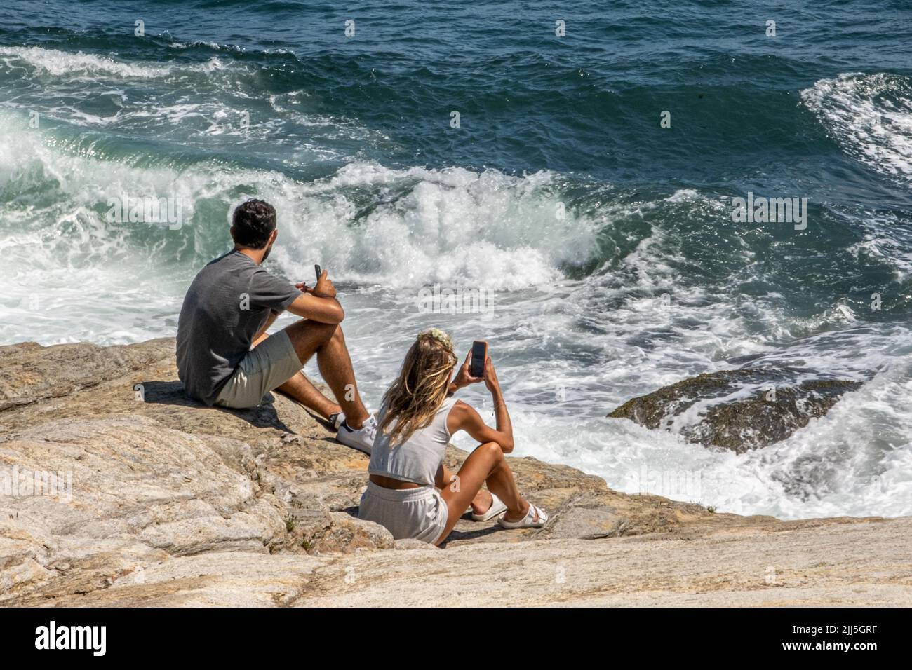Pareja sentada en las rocas en Beaver Tail en Jamestown, Rhode Islans Foto de stock