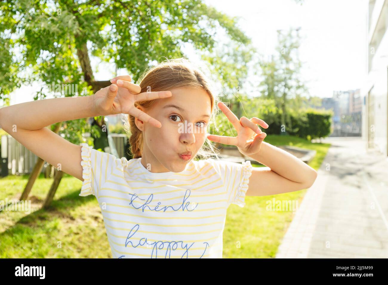 Chica mostrando un signo de paz delante del árbol Foto de stock