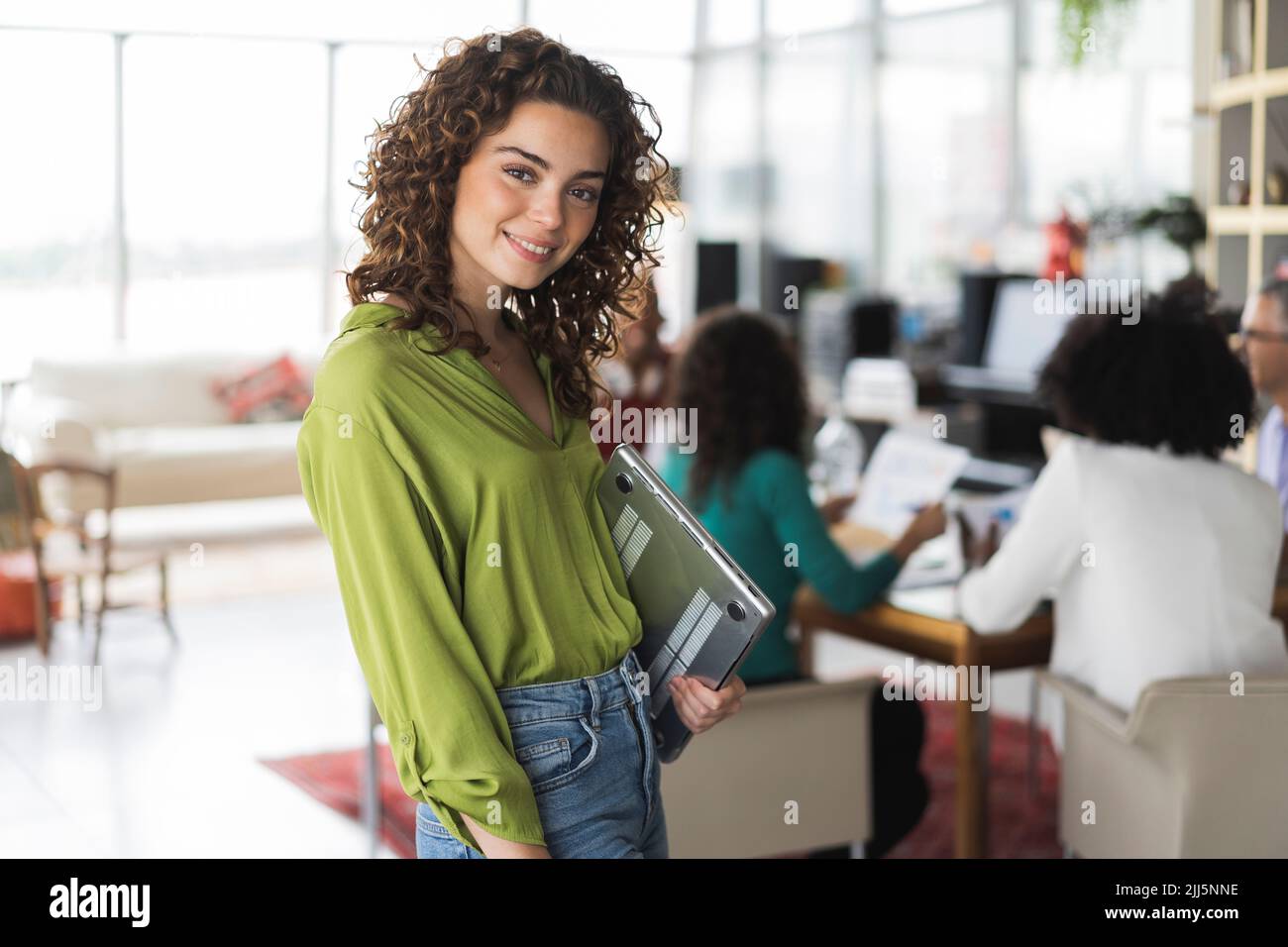 Mujer de negocios sonriente con un ordenador portátil en la oficina Foto de stock