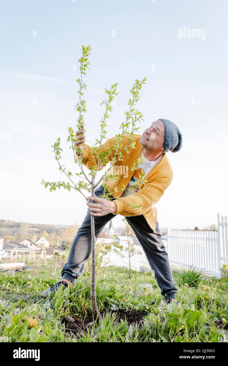 Hombre maduro que usa sombrero de punto plantando en jardín Foto de stock