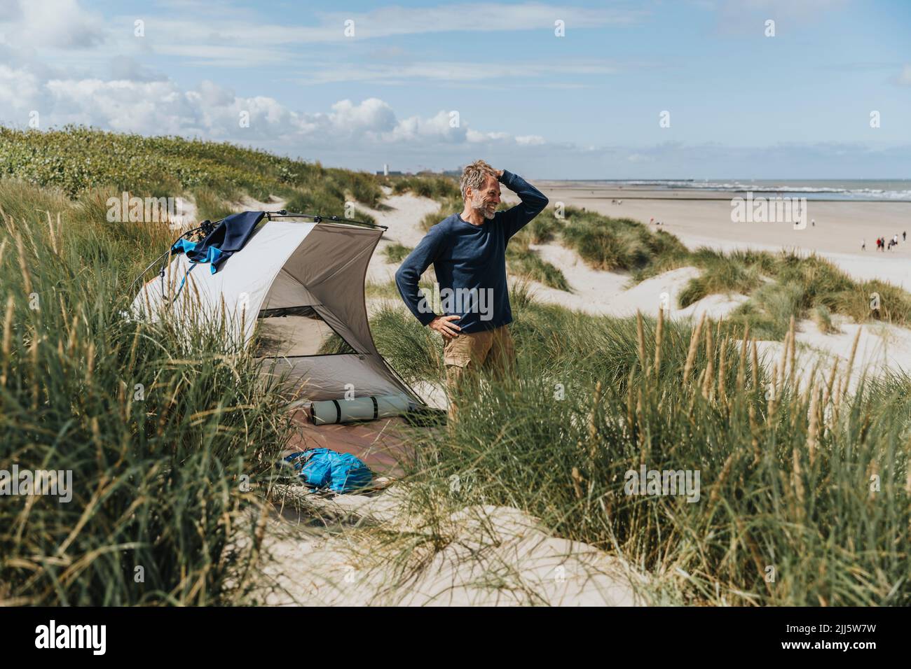 Hombre feliz acampando en un día soleado en la playa Foto de stock