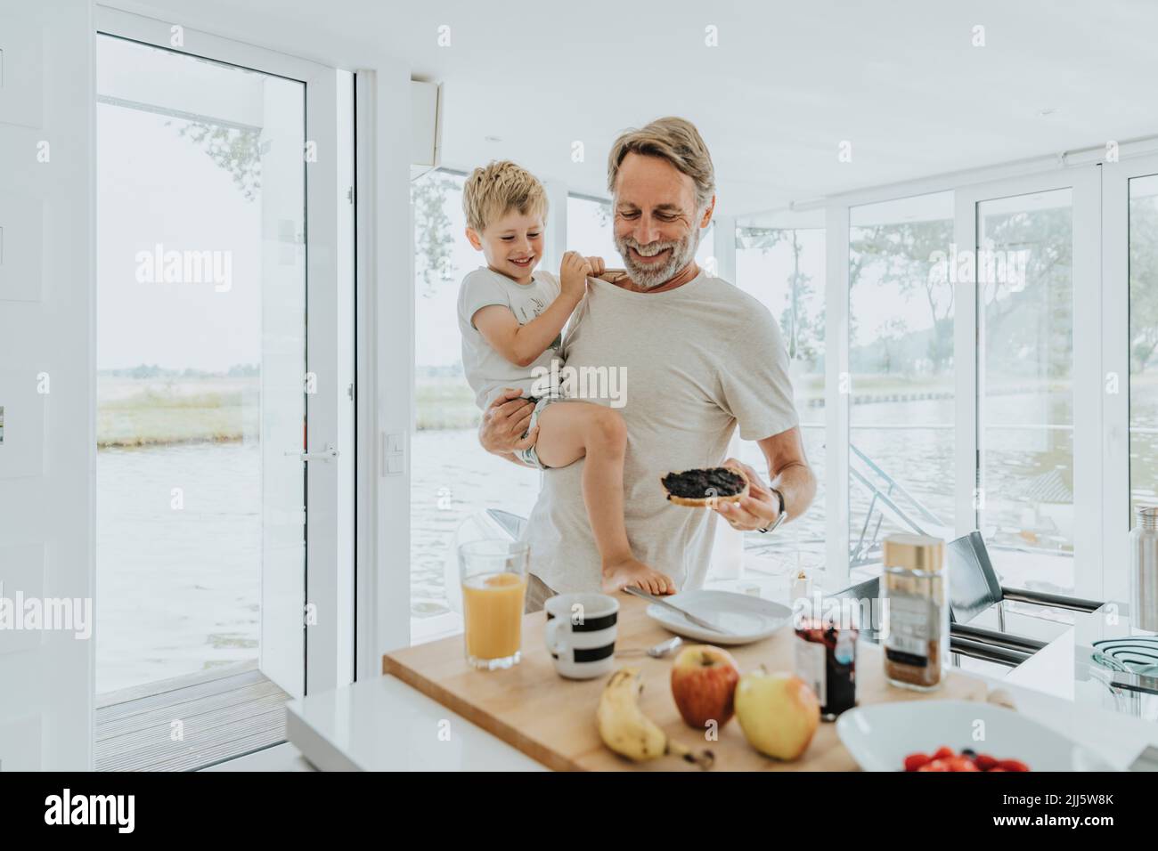 Padre feliz con su hijo desayunando en casa Foto de stock