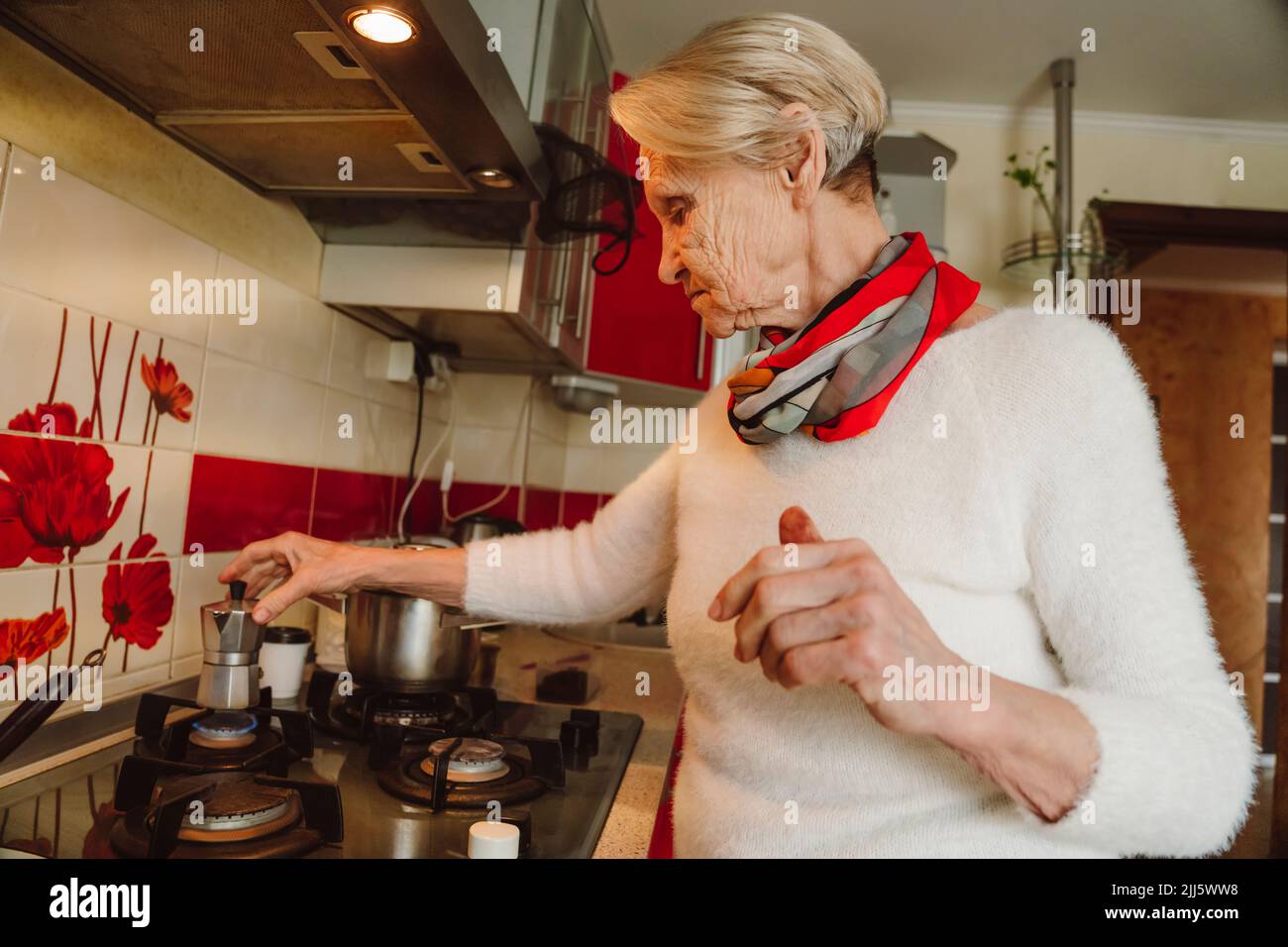 Mujer mayor preparando café en la cocina en casa Foto de stock