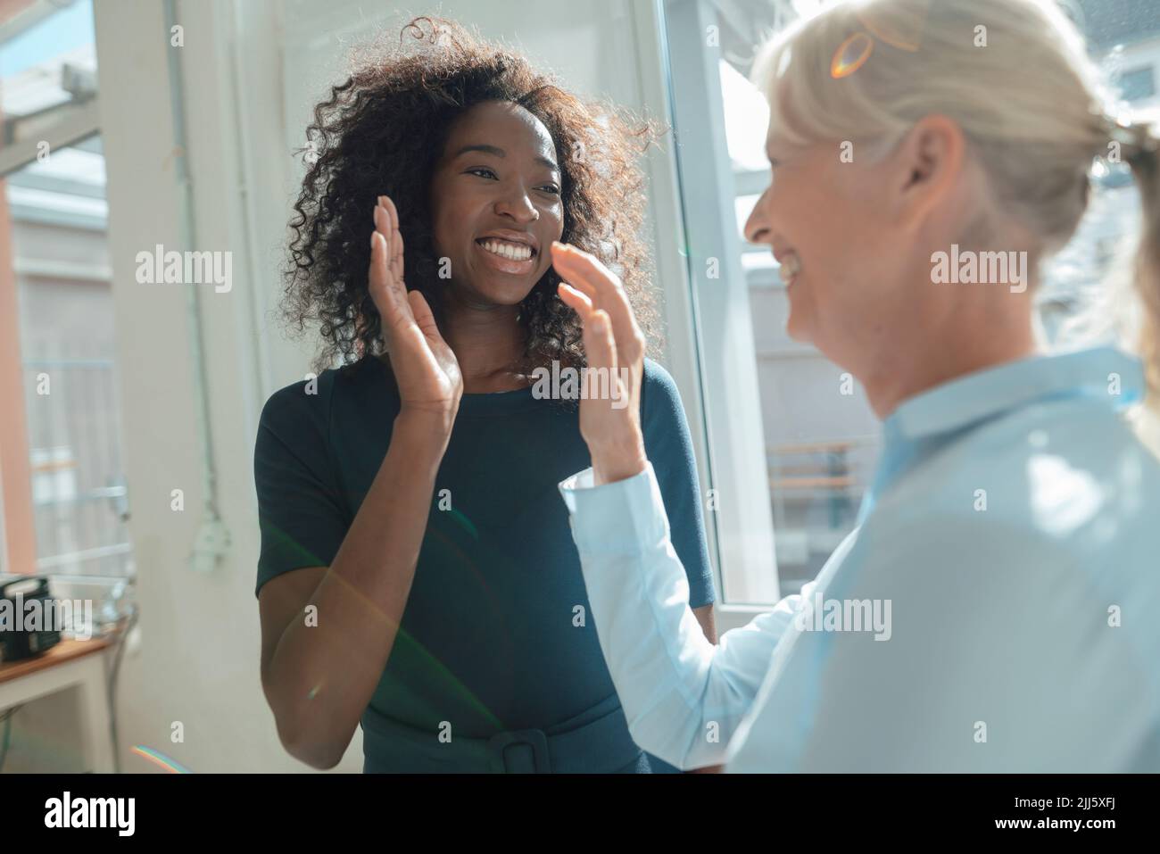 Mujer de negocios sonriente dando cinco años de alta a un compañero de trabajo Foto de stock