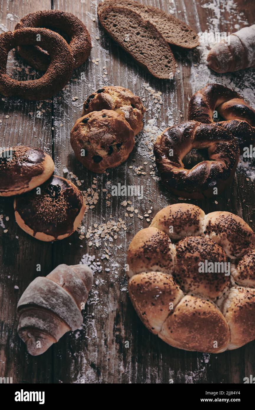 Desde arriba diferentes tipos de dulces al horno colocados sobre una mesa de madera desordenada con pan turco fresco en una panadería ligera Foto de stock