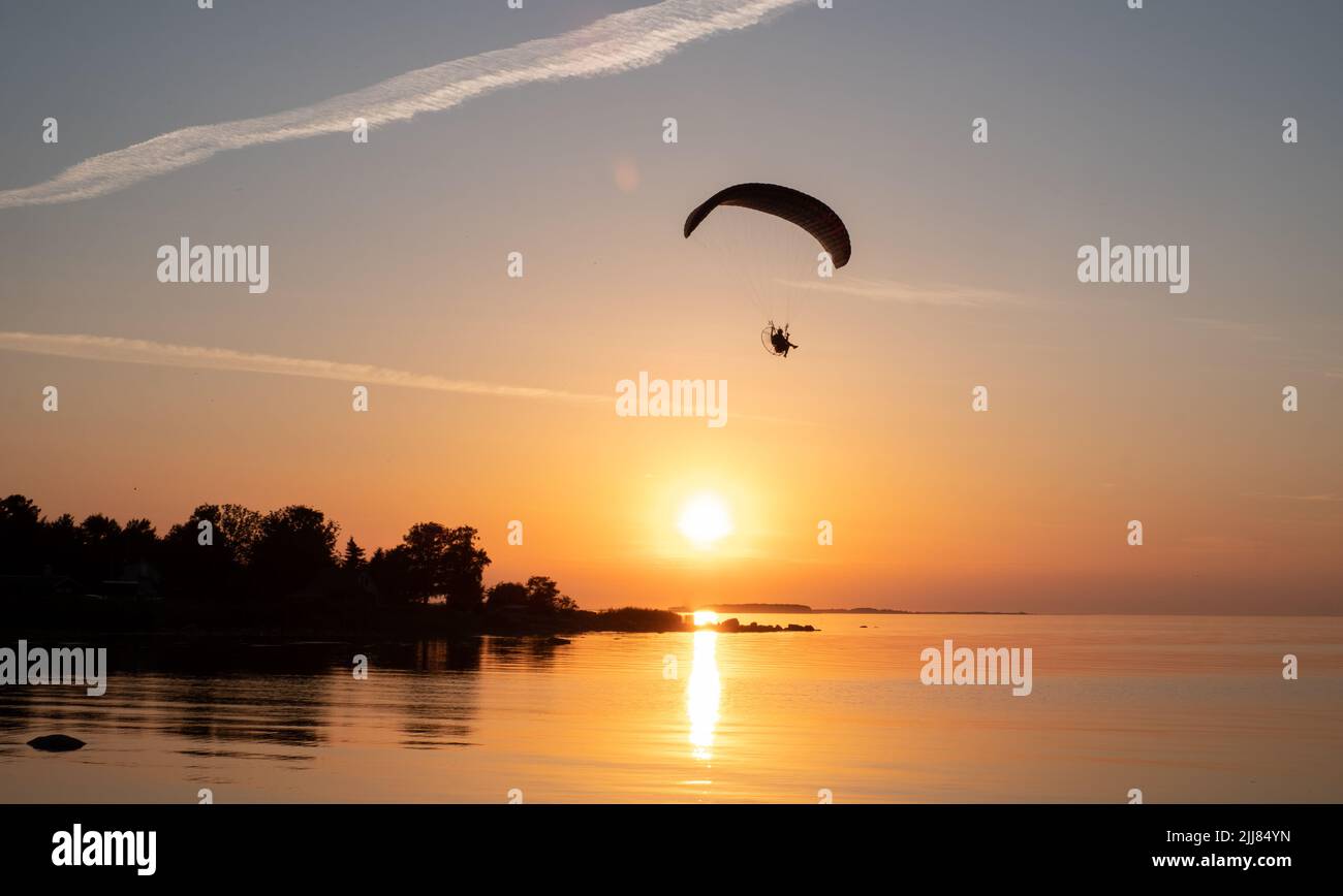 El piloto de parapente vuela en el cielo durante la puesta de sol en una hermosa playa. Silueta Paraplásica. Vacaciones de aventura y concepto de viajes. Foto de stock