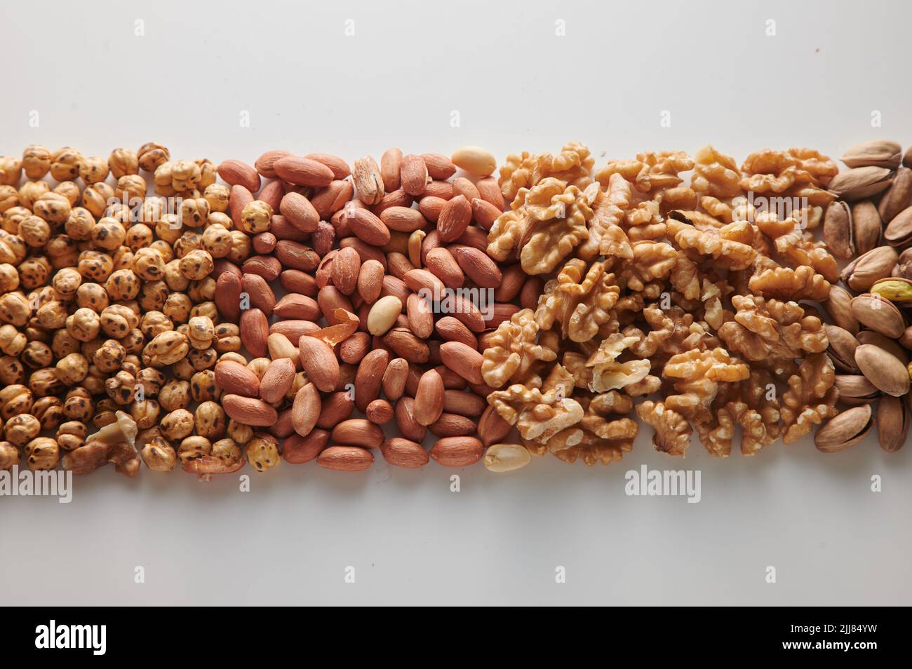Vista superior montón de avellanas con cacahuetes sin pelar colocados sobre fondo blanco claro con nueces y pistachos en estudio luminoso Foto de stock