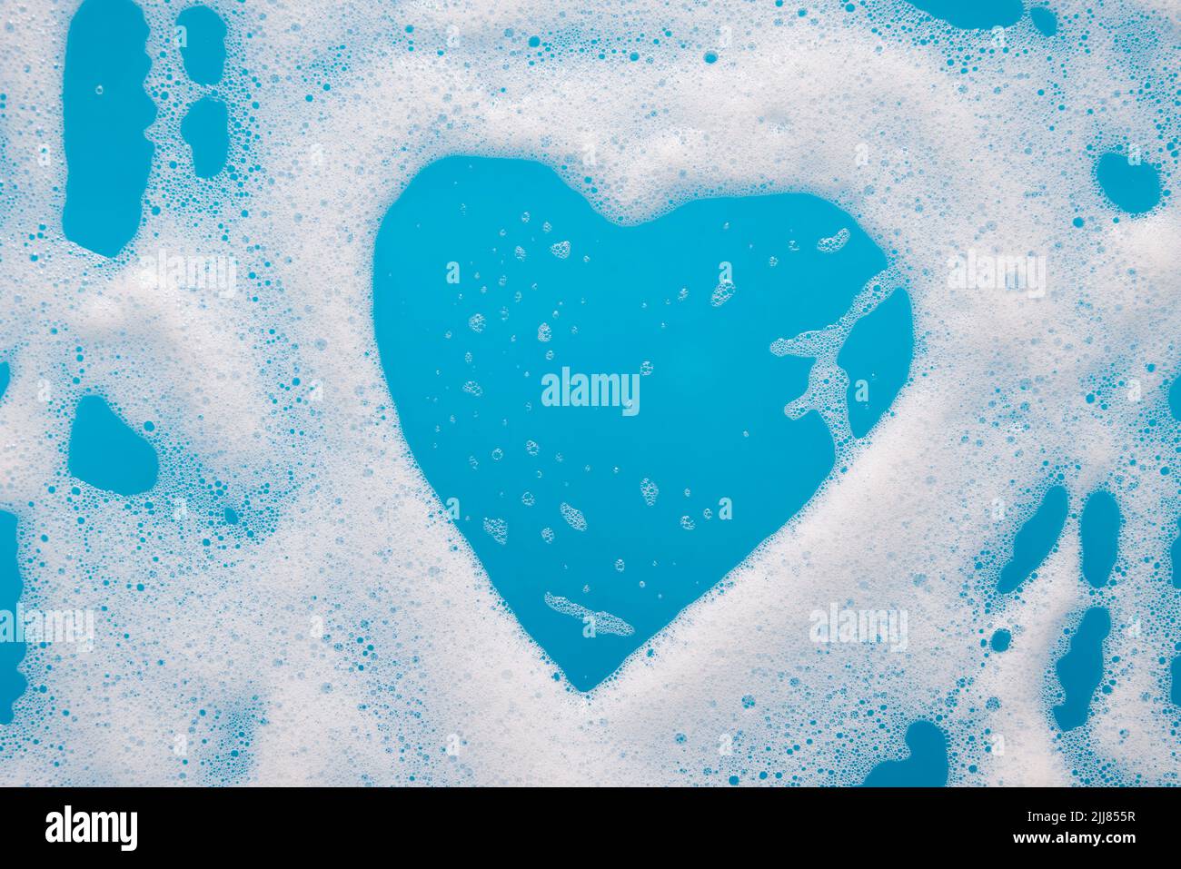 Espuma azul en forma de corazón en una bañera Foto de stock