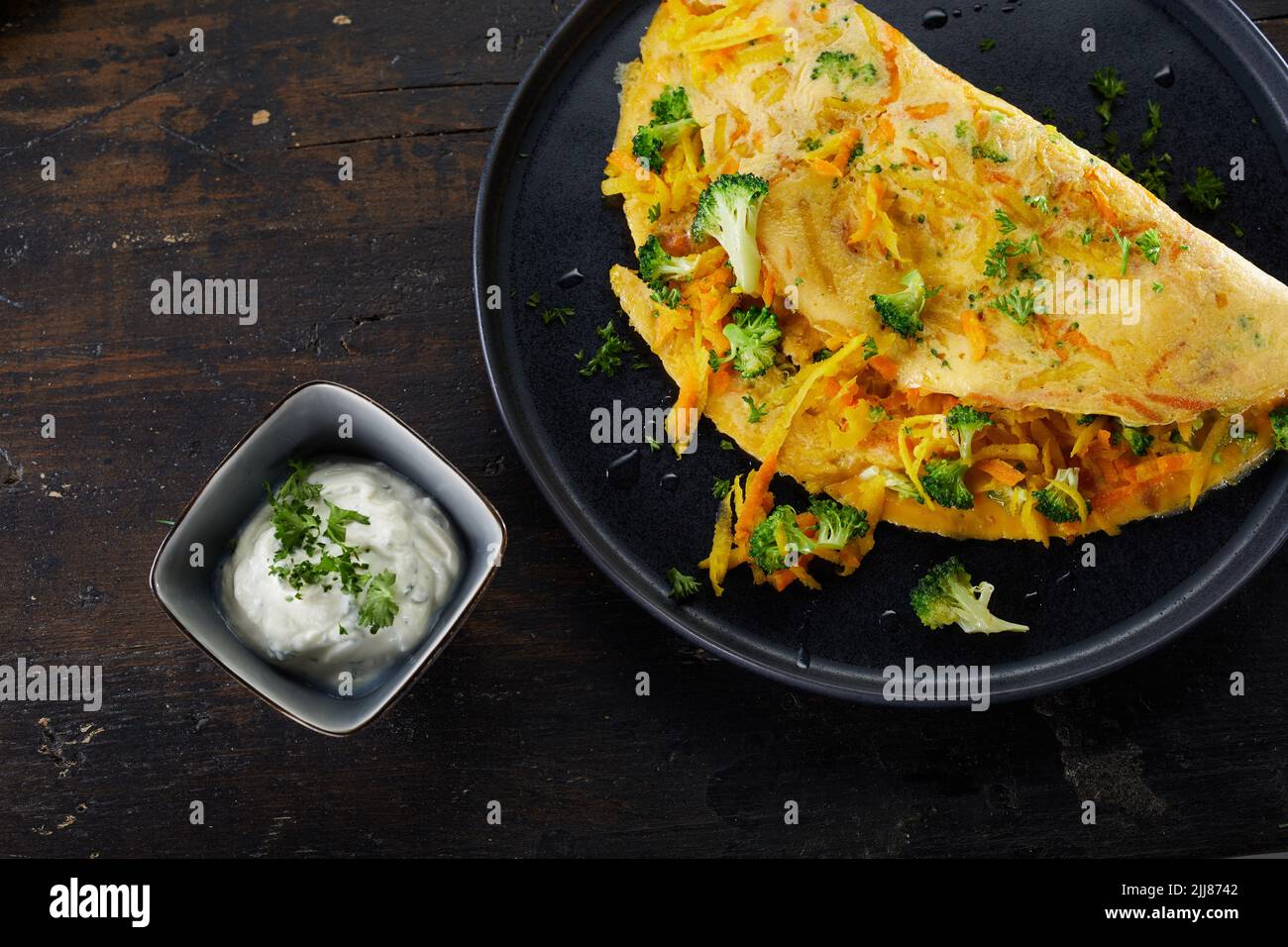 Vista superior de una sabrosa tortilla con zanahoria y brócoli servida en la mesa con crema agria para el almuerzo Foto de stock