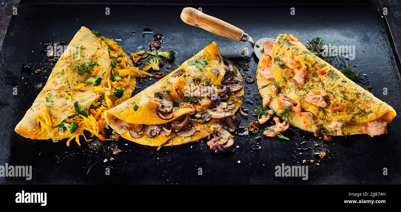 Desde arriba de deliciosas tortillas variadas con ingredientes frescos colocados en bandeja de horno con espátula en la cocina Foto de stock