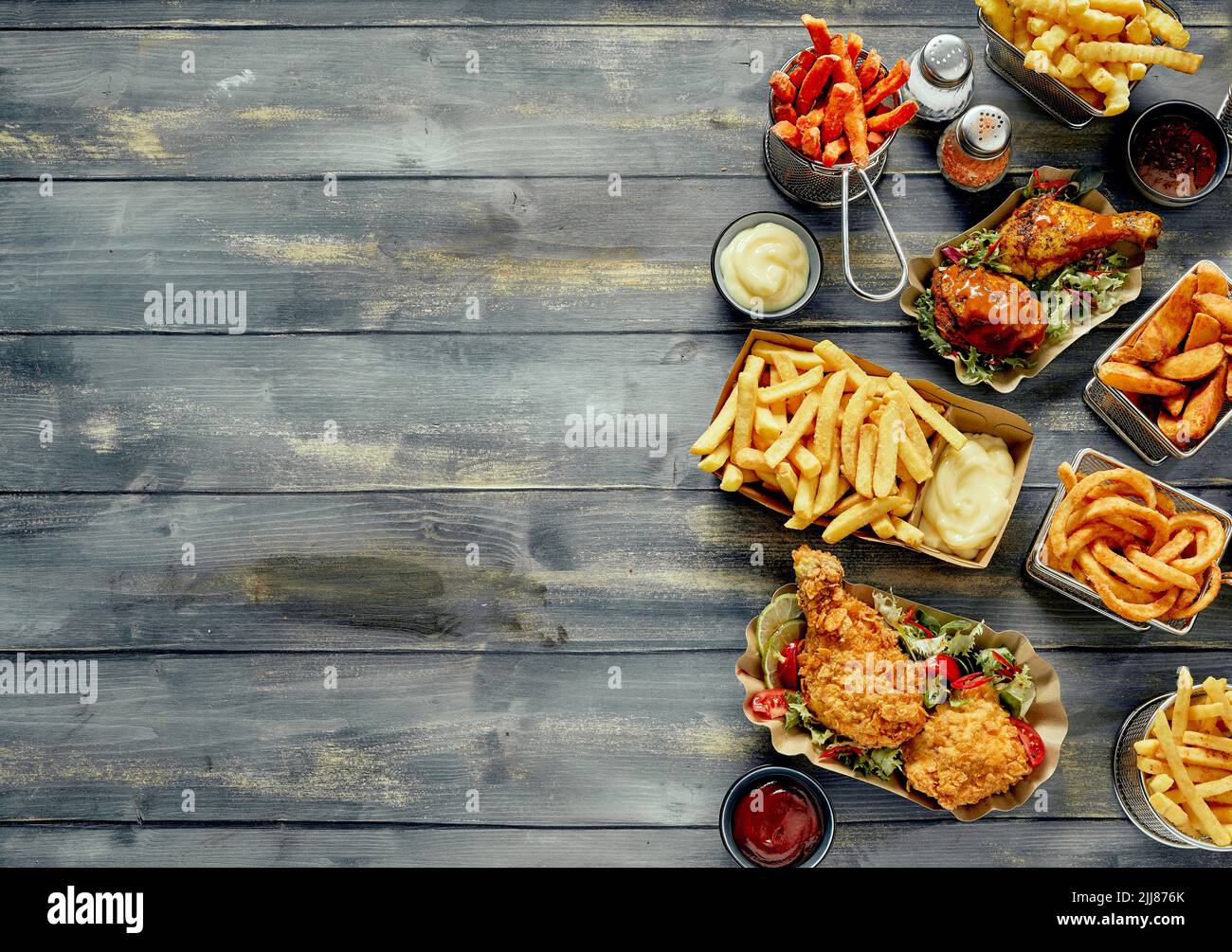 Vista superior de una variedad de sabrosos platos de comida rápida y salsas arregladas sobre una mesa de madera Foto de stock