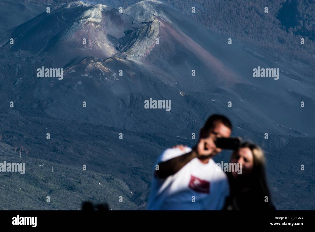 Una pareja es fotografiada con el cono del volcán Tajogaita al fondo. La Palma, Islas Canarias, España Foto de stock