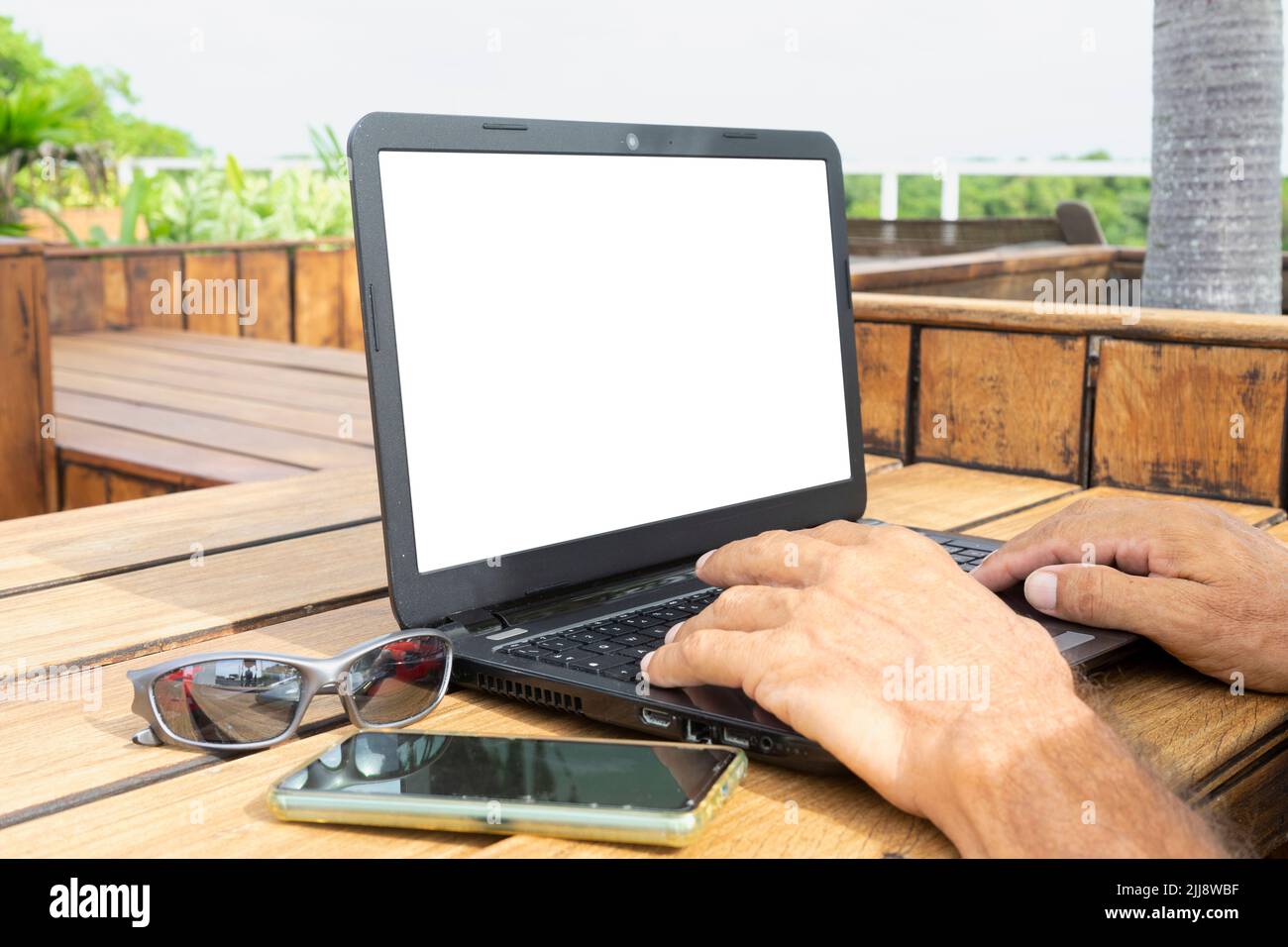 Toma de un nómada digital trabajando en un ordenador portátil en un café al aire libre. Enfoque selectivo. Foto de stock