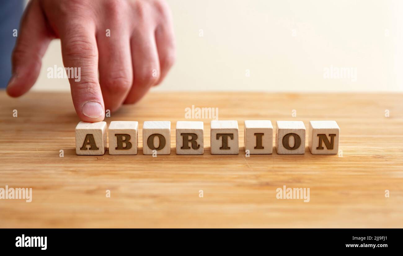 Aborto, concepto de interrupción del embarazo. Mano masculina y aborto Texto sobre bloques de madera, espacio de copia. Foto de stock