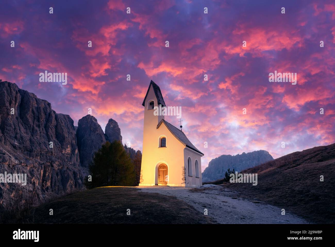 Increíble vista en la pequeña capilla iluminada - Kapelle Ciapela en Gardena Pass, las montañas Dolomitas italianas. Puesta de sol colorida en los Alpes Dolomitas, Italia. Fotografía de paisajes Foto de stock