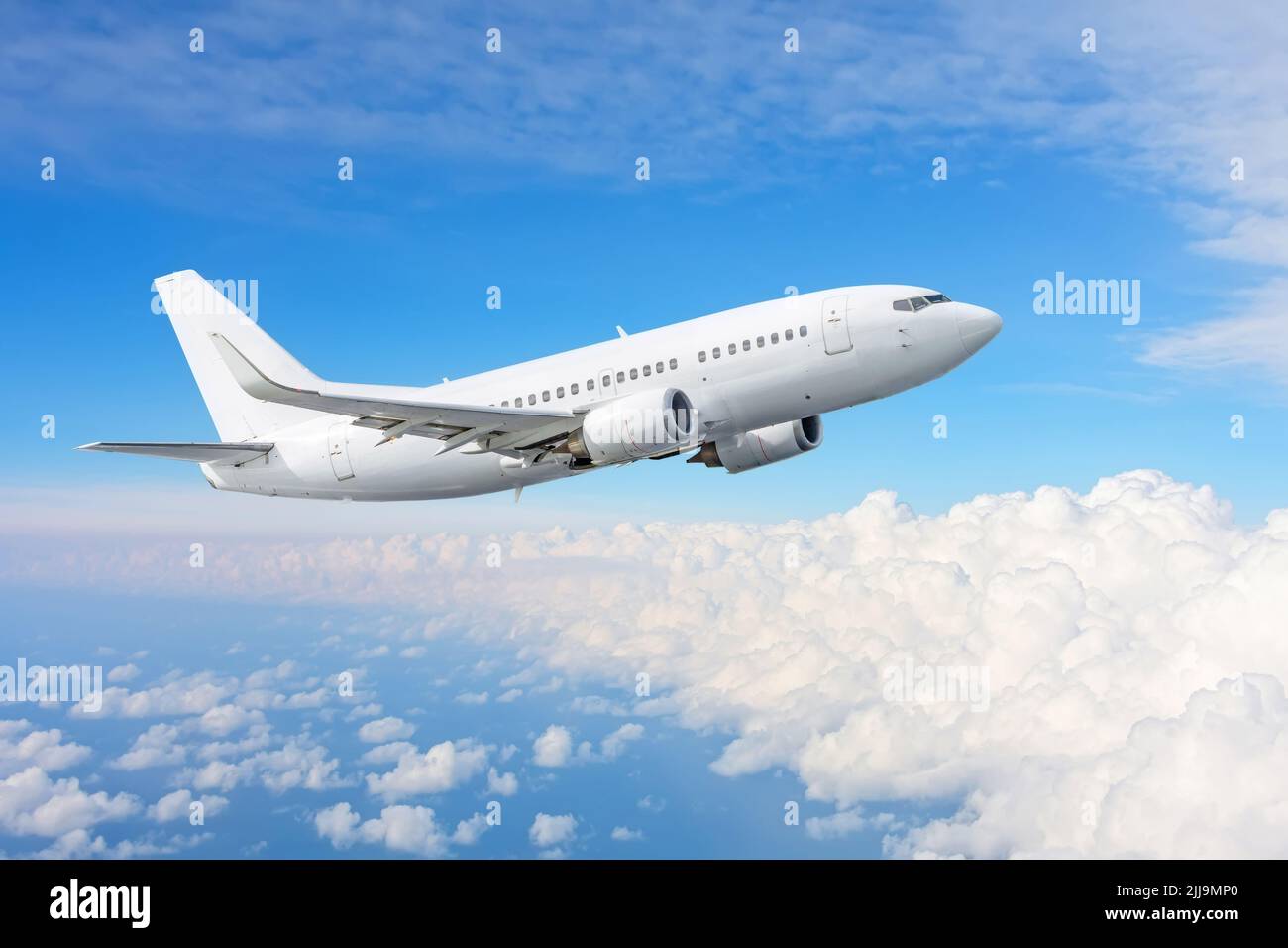 El avión de color blanco vuela alto en el cielo sobre las nubes Foto de stock