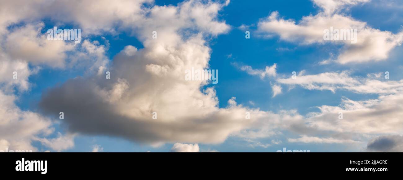 Una imagen detallada de nubes cumulus fluffy blancas contra un cielo azul diurno en formato de imagen de banner Foto de stock