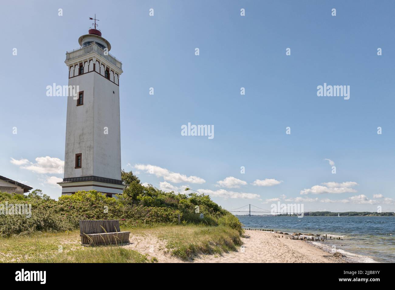 Strib FYR, faro en la playa de Middelfart, Funen, Dinamarca, con el pequeño puente Belt en el fondo Foto de stock