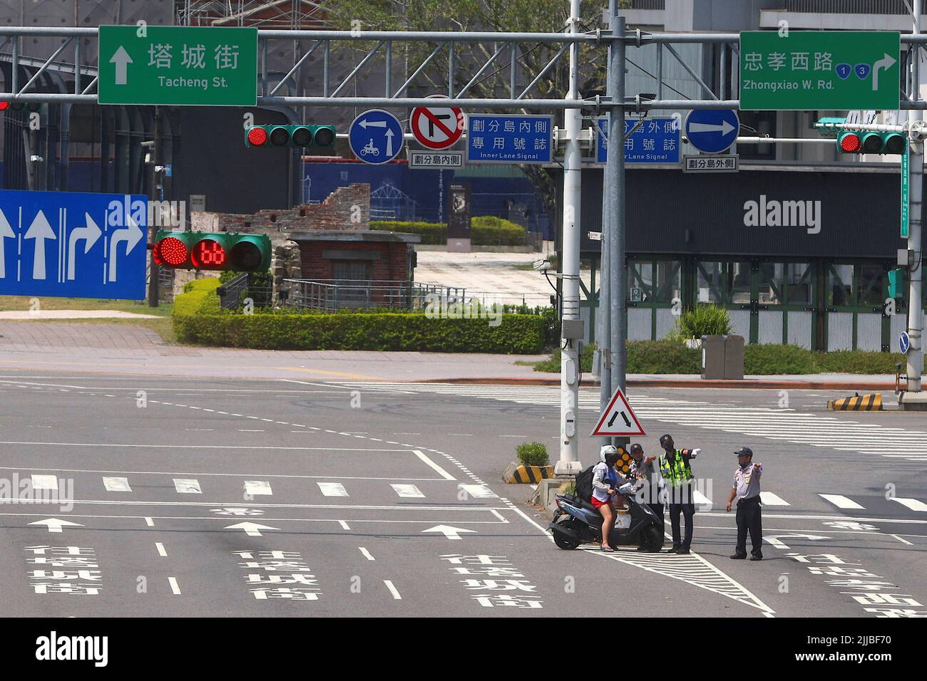 Una mujer en una moto debe protegerse durante el ejercicio de allanamiento aéreo llamado Wan An, un ejercicio anual de 30 minutos, un recordatorio de la creciente amenaza militar china, Durante el cual se ordena a todos los vehículos moverse a los lados de los caminos y peatones para esperar en las calles secundarias en Taipei, Taiwán, 25 de julio de 2022. REUTERS/Ann Wang Foto de stock