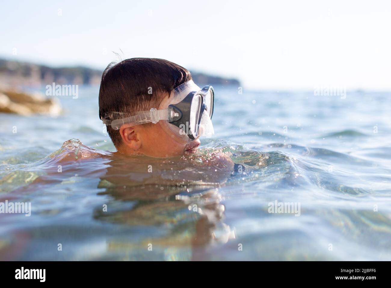 Joven buceador cansado en gafas soplando aire en el mar Foto de stock