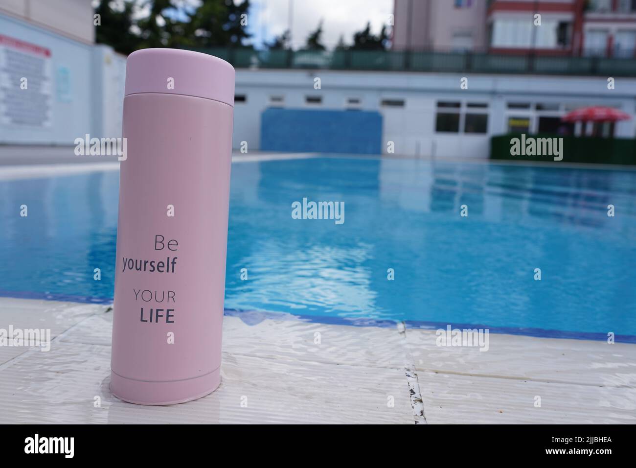 Un termo para café, té y agua con 'Sea usted mismo, su vida' escrito en él  junto a la piscina Fotografía de stock - Alamy