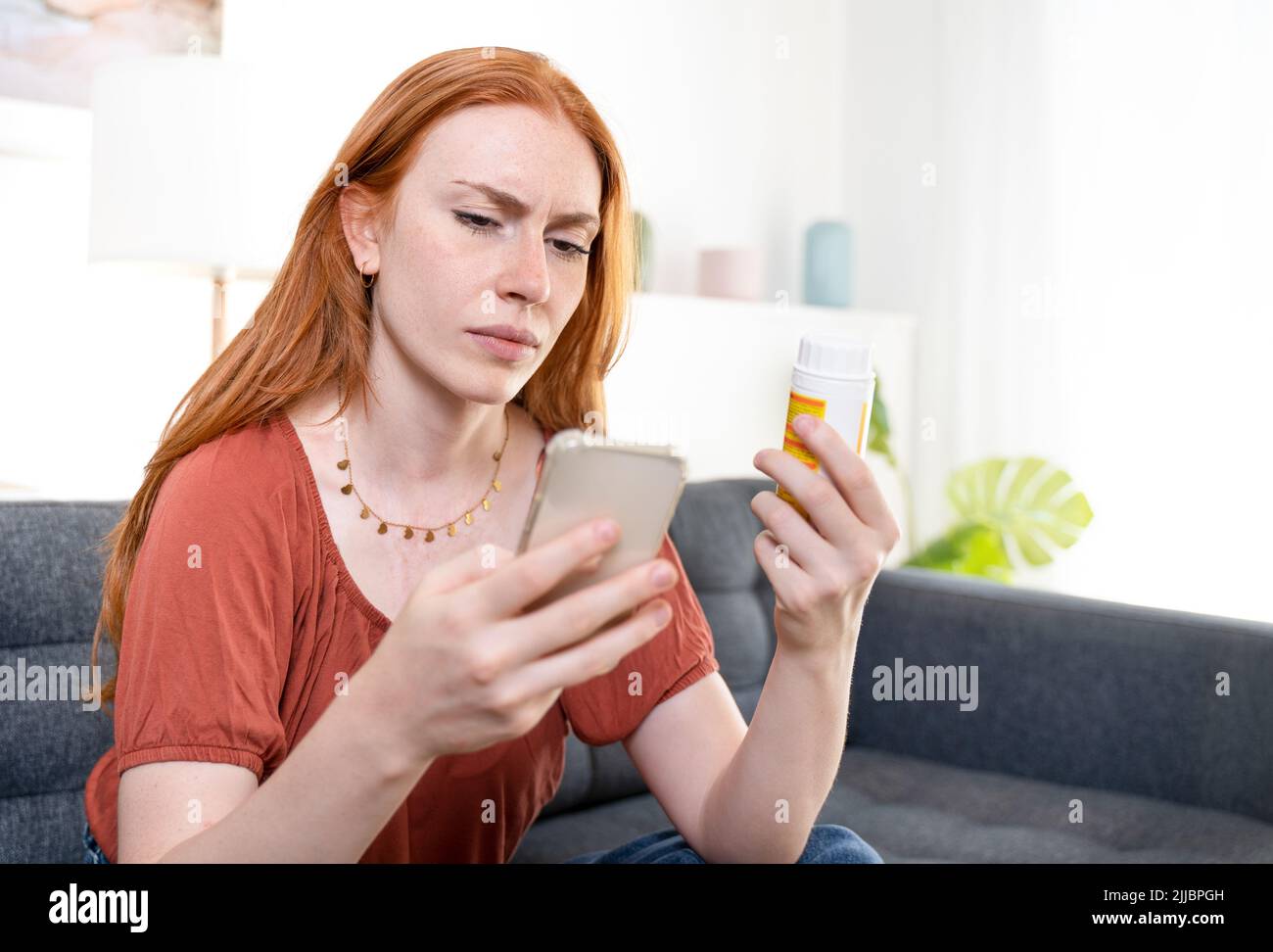 Mujer revisando los componentes de la píldora en Internet Foto de stock