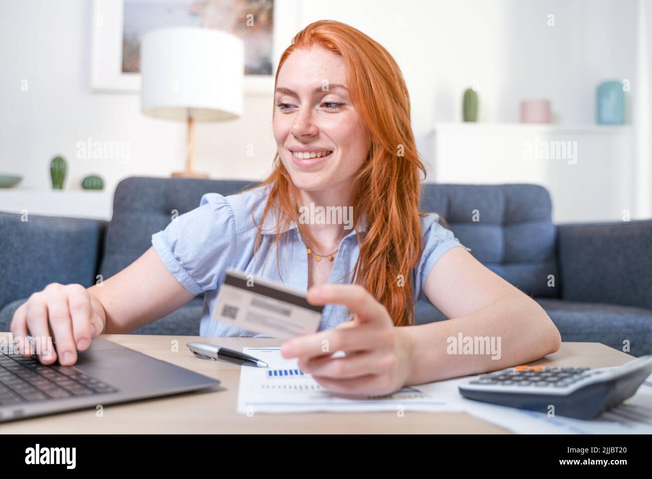 Mujer feliz usando la compra con tarjeta de crédito en casa Foto de stock