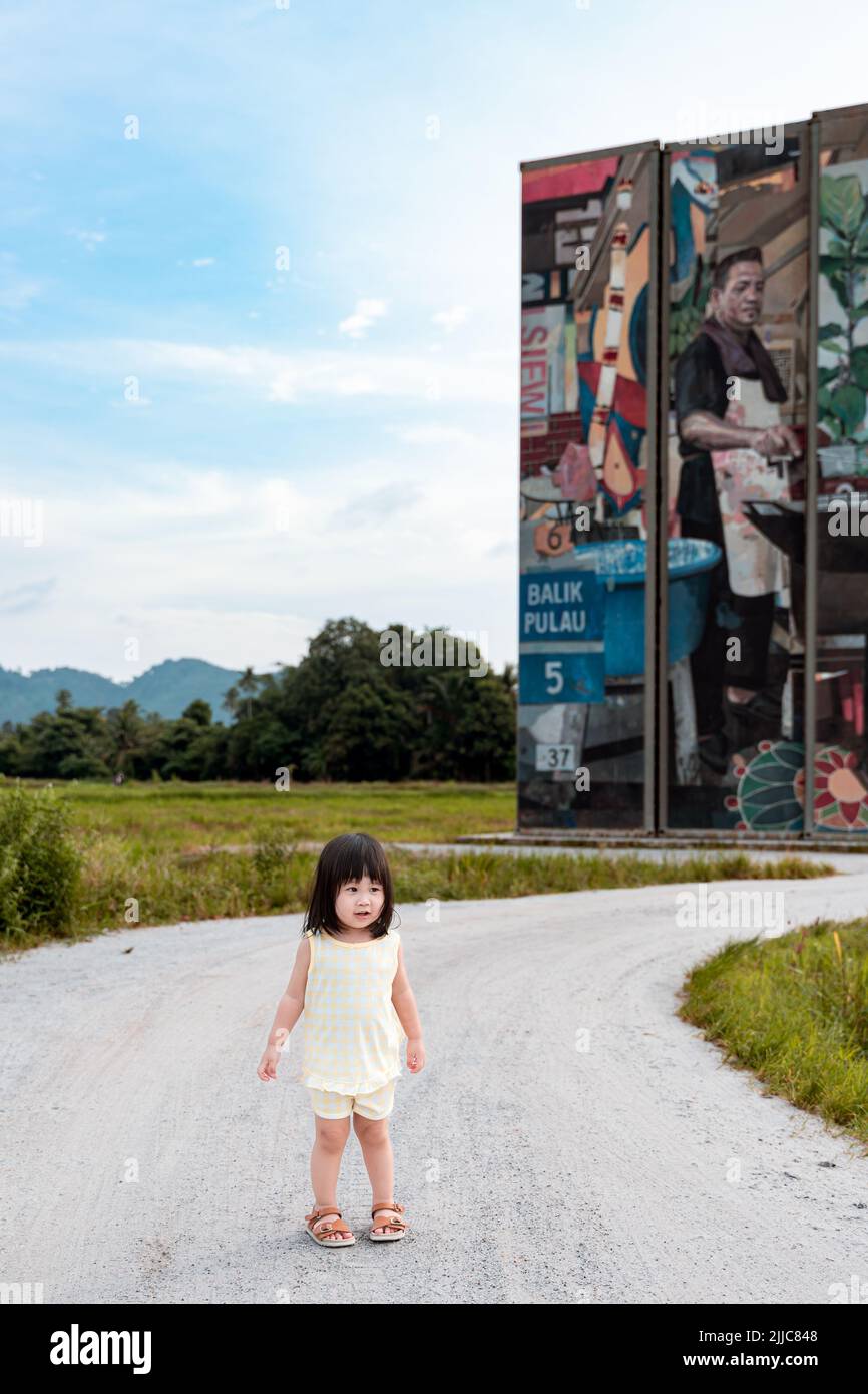 Pequeña chica que posaba delante del arte del contenedor. La obra de arte fue exhibida en balik pulau, Penang. Foto de stock