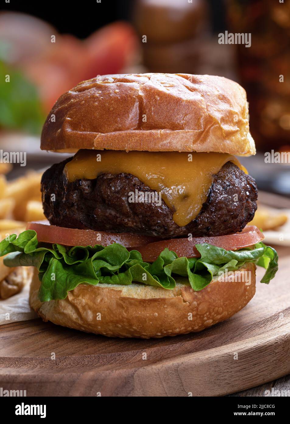 Primer plano de hamburguesa de queso con lechuga y tomate sobre una bandeja de madera Foto de stock