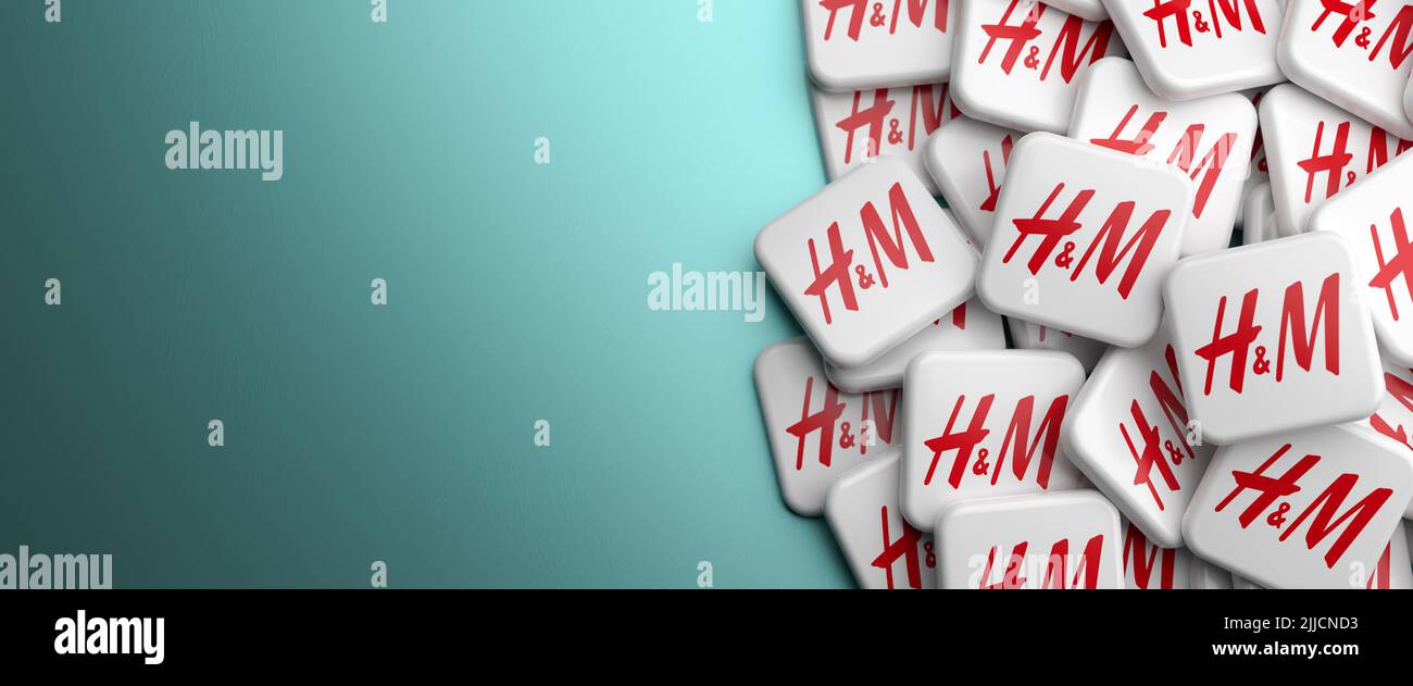 Logotipos de la empresa de ropa Swedisch H&M Hennes&Mauritz sobre un montón en una mesa. Espacio de copia. Formato de banner web. Foto de stock