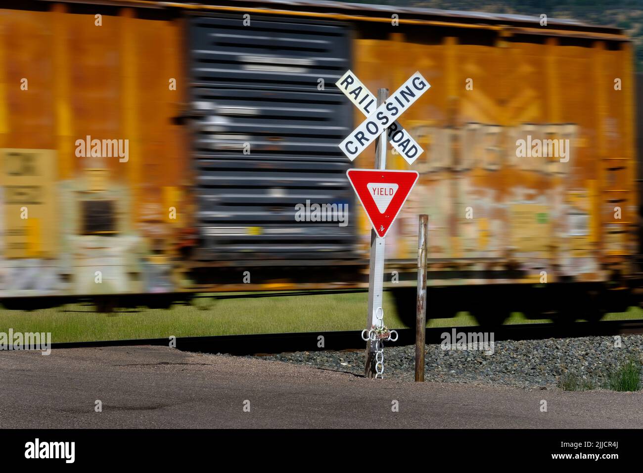 Señal de cruce de ferrocarril con vagones de ferrocarril y motor velando borroso por el transporte de artículos Foto de stock
