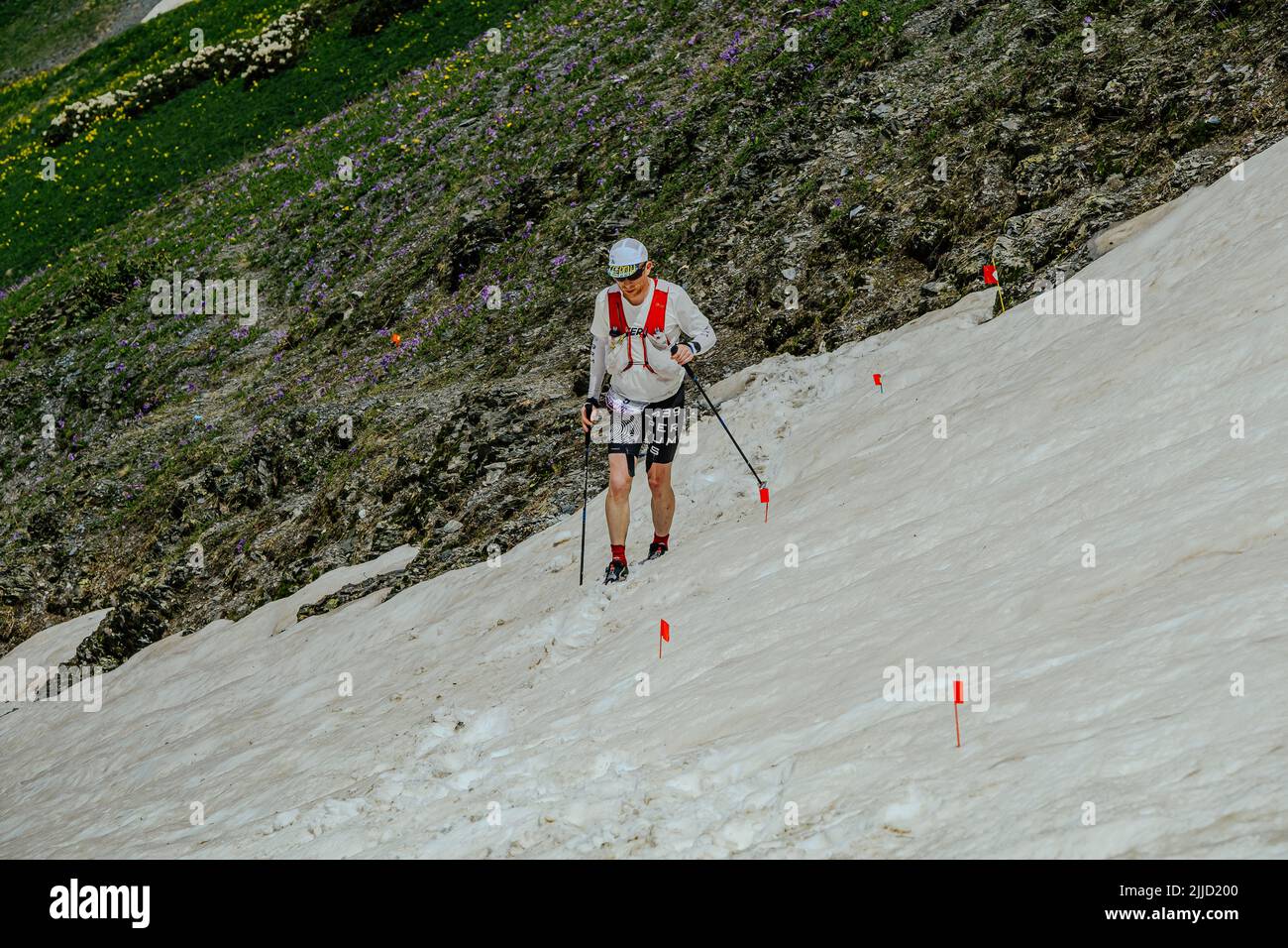 Arkhyz, Rusia - 2 de julio de 2022: Atleta masculino caminando nevado cuesta arriba en Arkhyz X Run Foto de stock