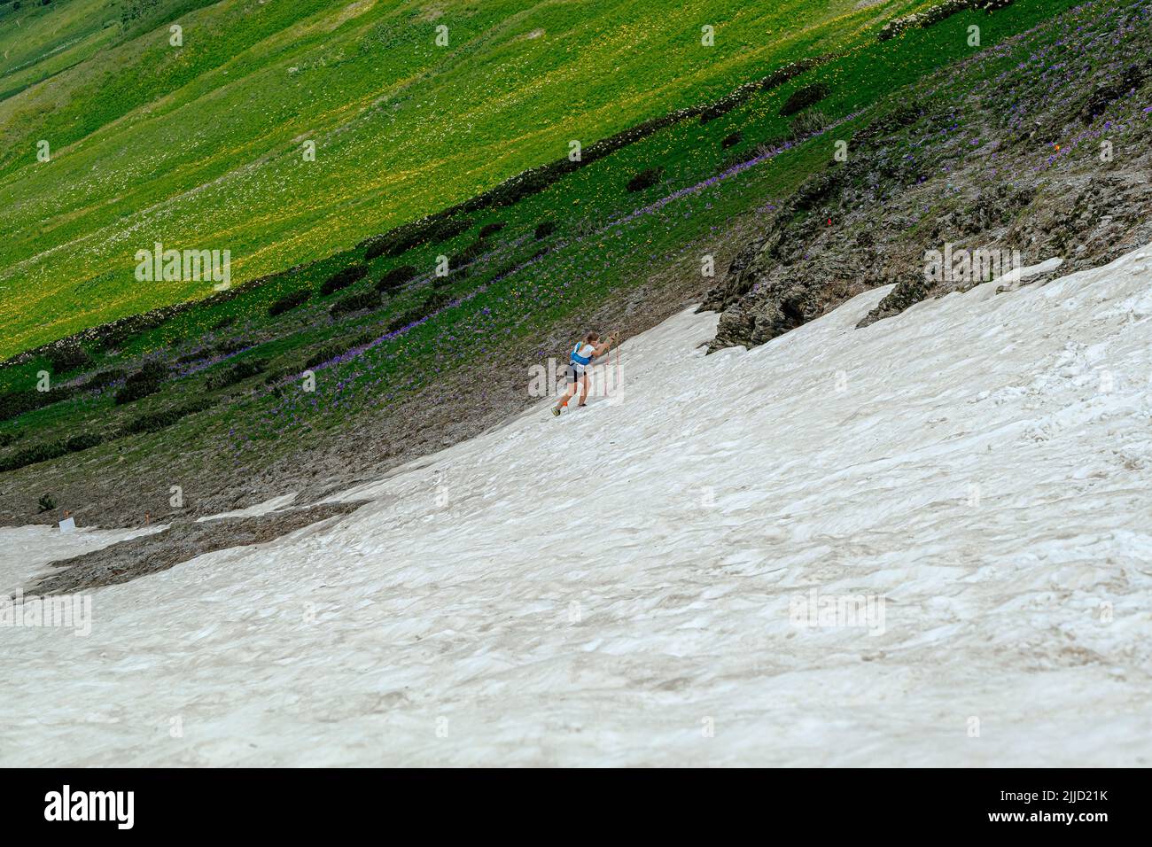 Arkhyz, Rusia - 2 de julio de 2022: Atleta femenino caminando nevado cuesta arriba en Arkhyz X Run Foto de stock