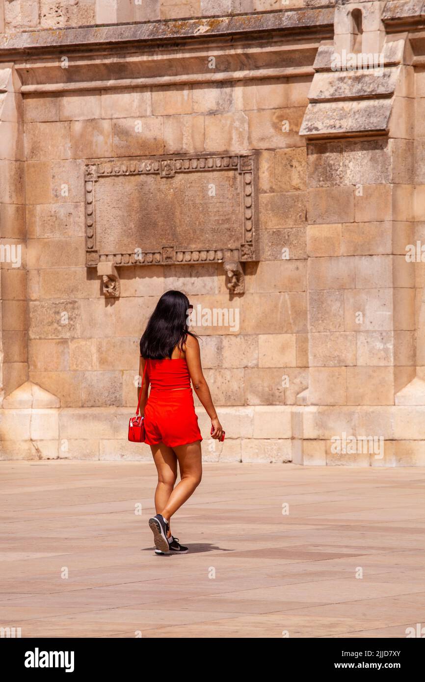 Mujer vestida de rojo caminando por la catedral de Santa María la virgen en la ciudad española de Burgos Foto de stock