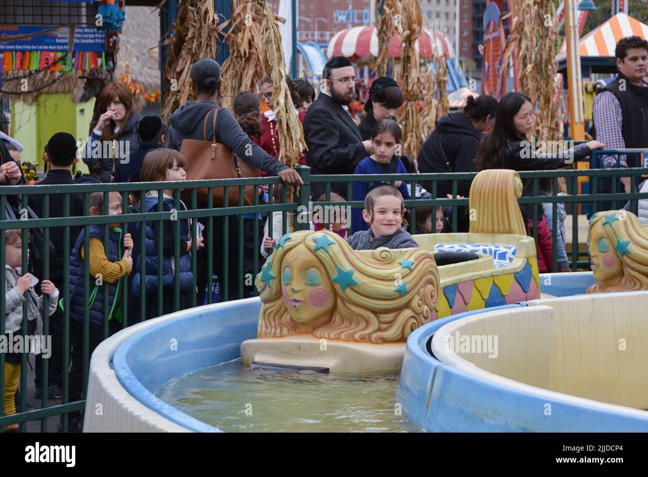 Las familias judías ortodoxas celebran la fiesta de Sukkos al divertirse en un parque de atracciones en Coney Island, Brooklyn, Nueva York. Foto de stock