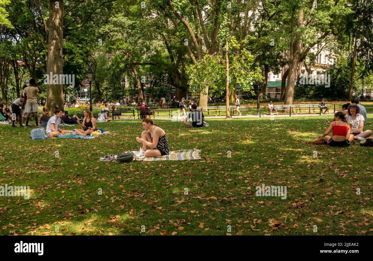 Los visitantes a Washington Square Park en Greenwich Village en Nueva York se relajan en el césped durante una ola de calor el domingo, 24 de julio de 20221. Las temperaturas sobrepasaron los 90 los últimos seis días con el pronóstico del lunes para que la ola de calor sea una semana par. (© Richard B. Levine) Foto de stock