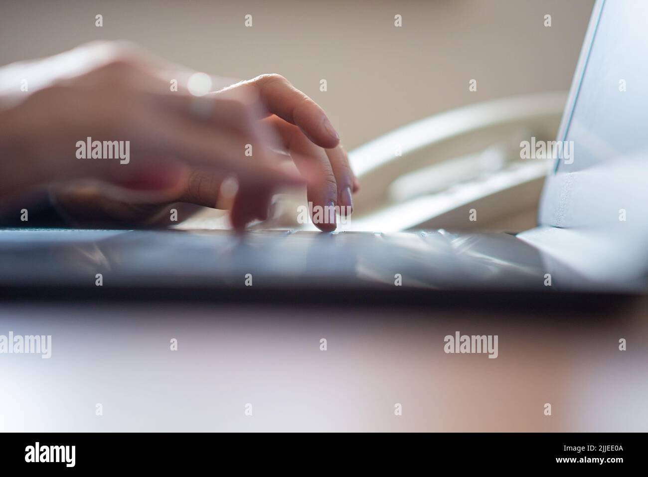 Vista de ángulo bajo de las manos femeninas escribiendo en un ordenador portátil. Movimiento borroso de los dedos. Foto de stock