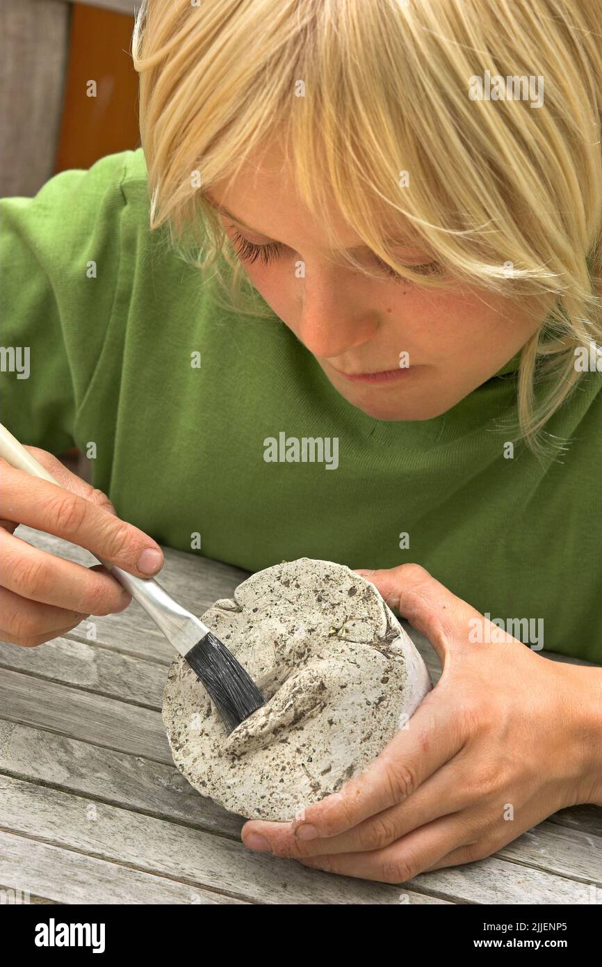 Niño que hace una copia de cemento del rastro de un corzo, Alemania Foto de stock