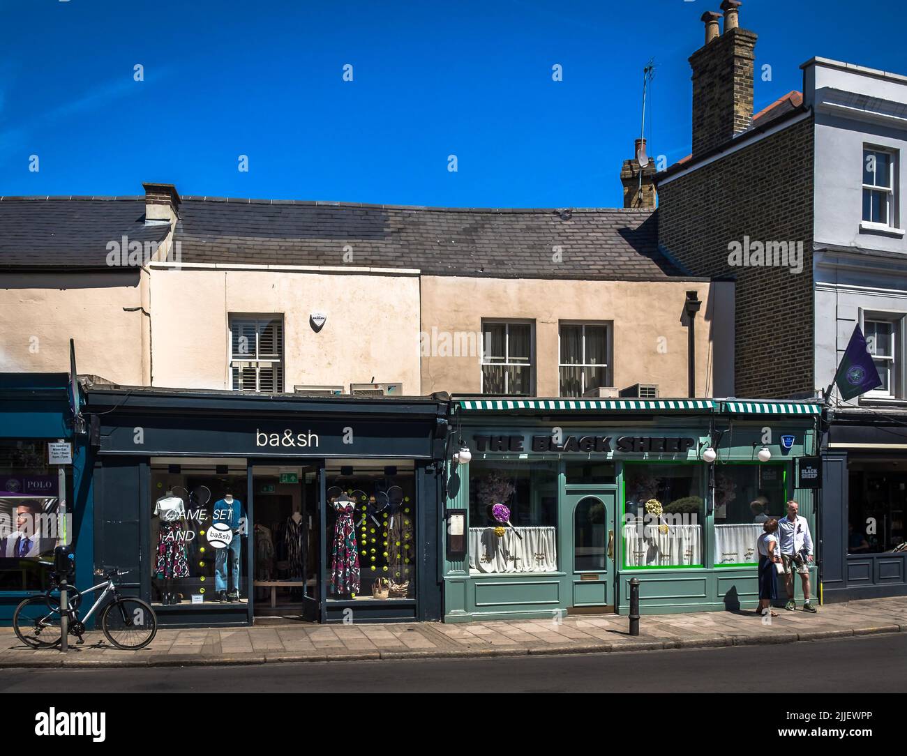 Londres, Reino Unido, 2022 de julio, vista de un restaurante y una tienda de ropa en Wimbledon Village decorado para la época del torneo. Foto de stock