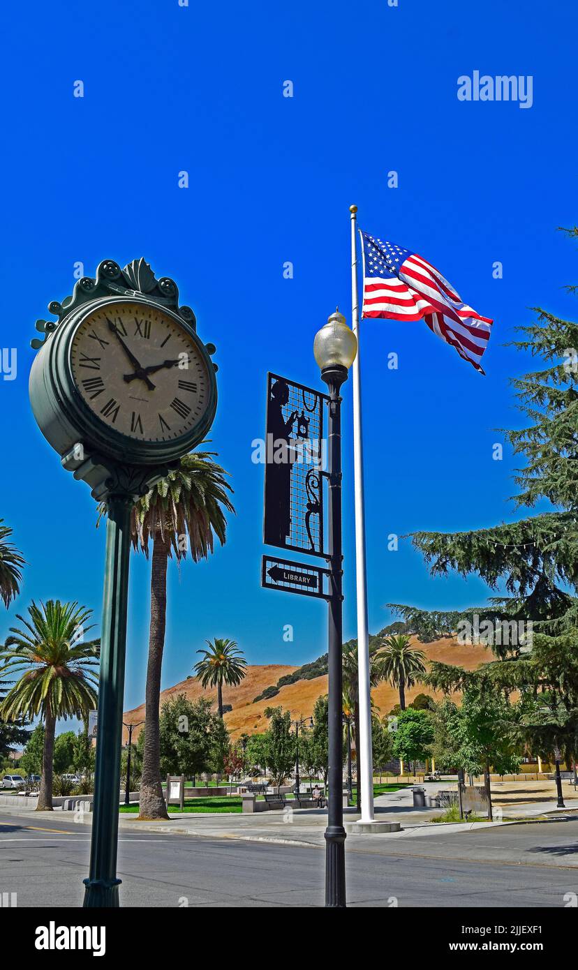 reloj, señal de dirección de la biblioteca, bandera americana y plaza de la ciudad en el districto de Niles de Fremont, California Foto de stock
