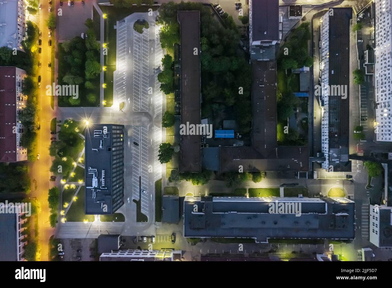 vista aérea de la zona industrial por la noche con edificios iluminados y aparcamiento vacío Foto de stock