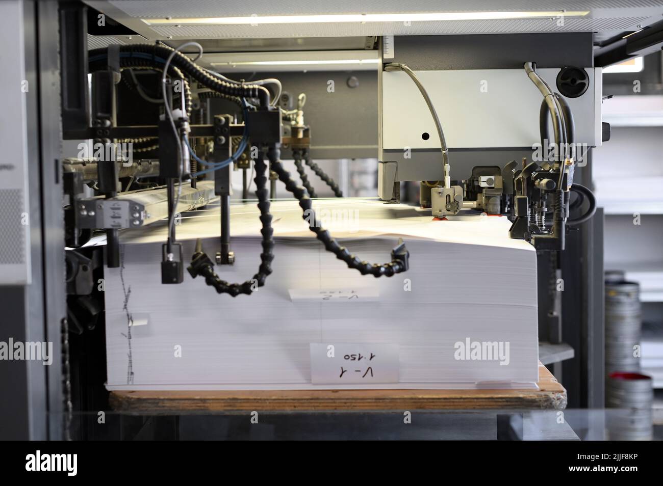 Máquina automática cargando pila de hojas de papel en la impresora offset industrial en taller de tipografía Foto de stock