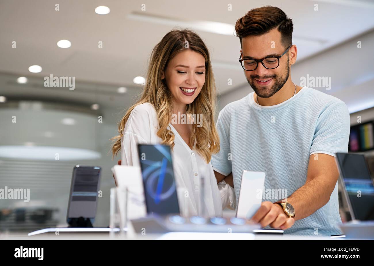 Comprar un nuevo dispositivo digital. Feliz pareja comprando un smartphone en la tienda. Foto de stock