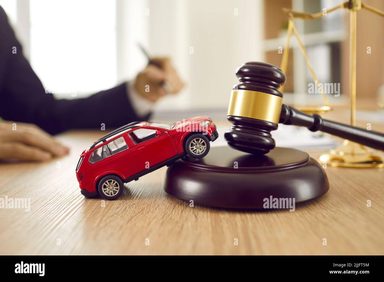 Pequeño automóvil de juguete en la mesa del abogado que ilustra el concepto de accidente de coche y pleito Foto de stock