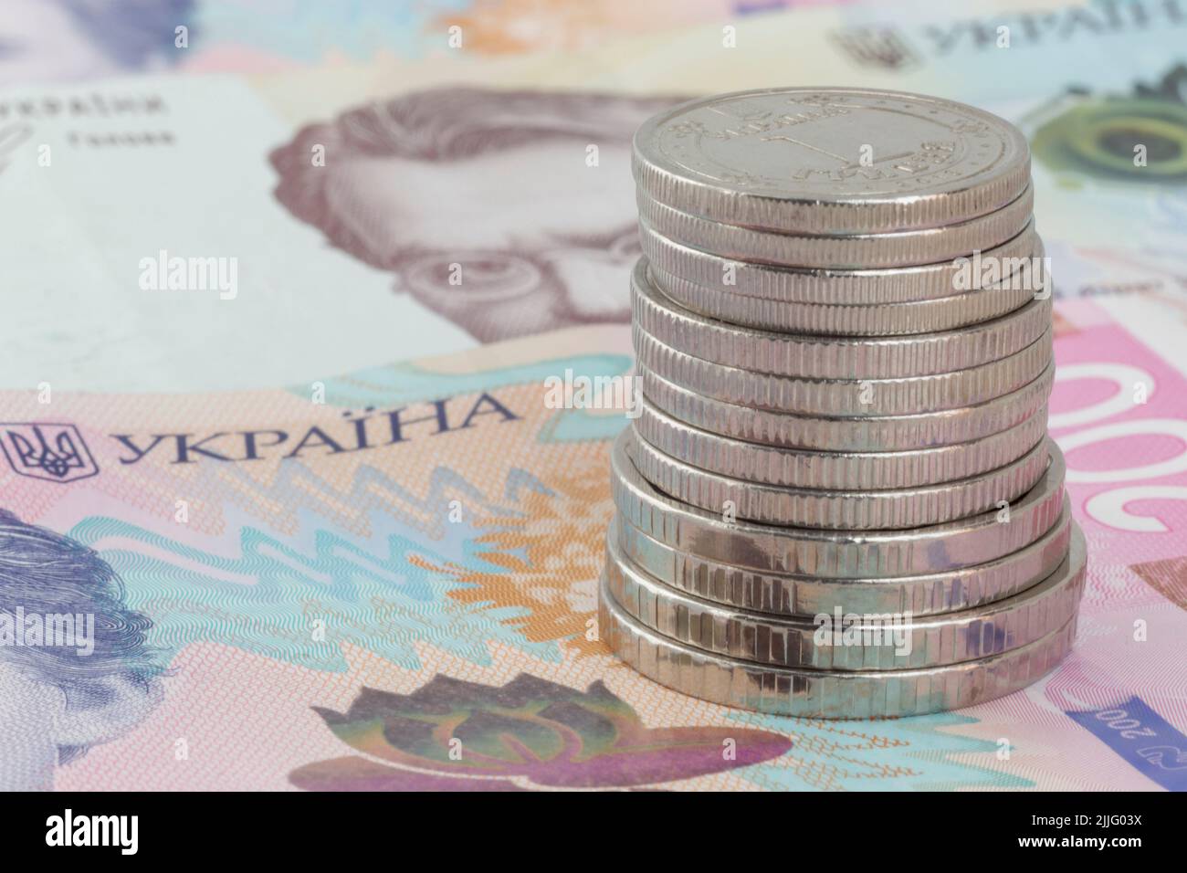 Pila de monedas ucranianas de hrivnya sobre doscientos billetes ucranianos de hrivnya Foto de stock