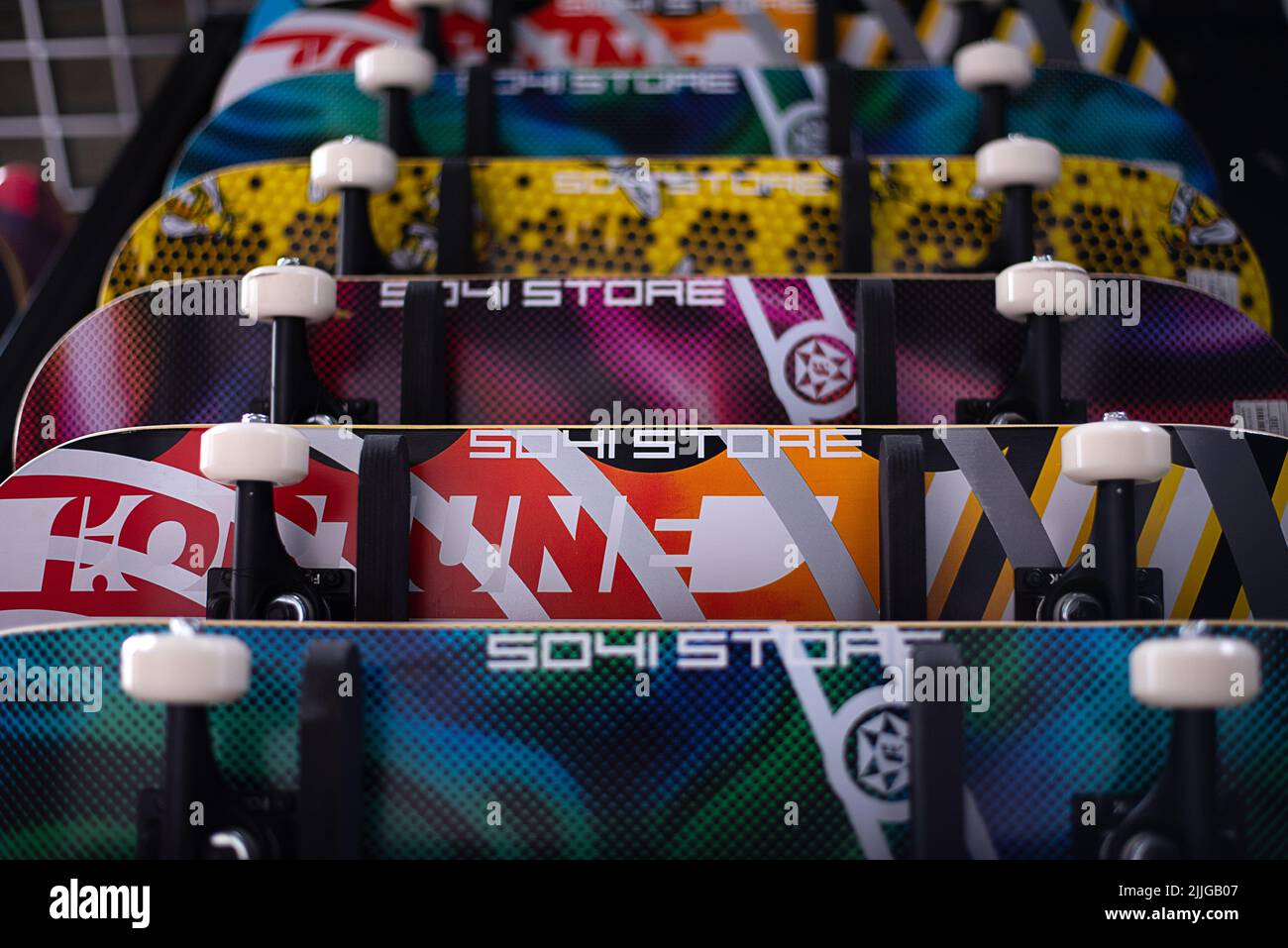 Muchos surfskate colgando en la pared de la tienda de skateboard. Muchos colores vibrantes. Foto de stock