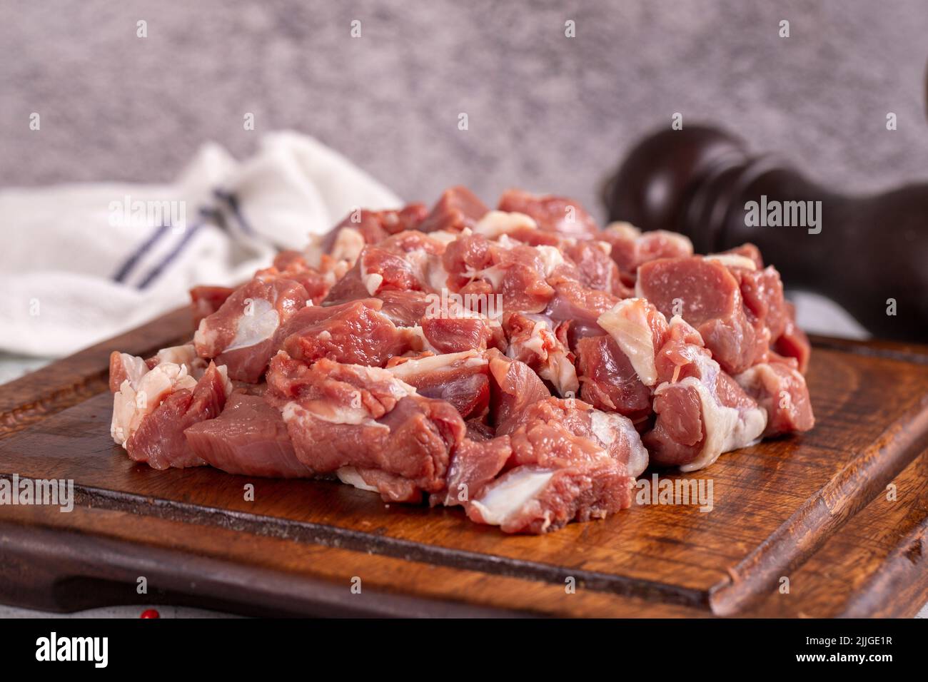 Carne de cordero en cubitos. Carne roja cortada en un plato de madera sobre un fondo de piedra. Productos de carnicero. Primer plano Foto de stock