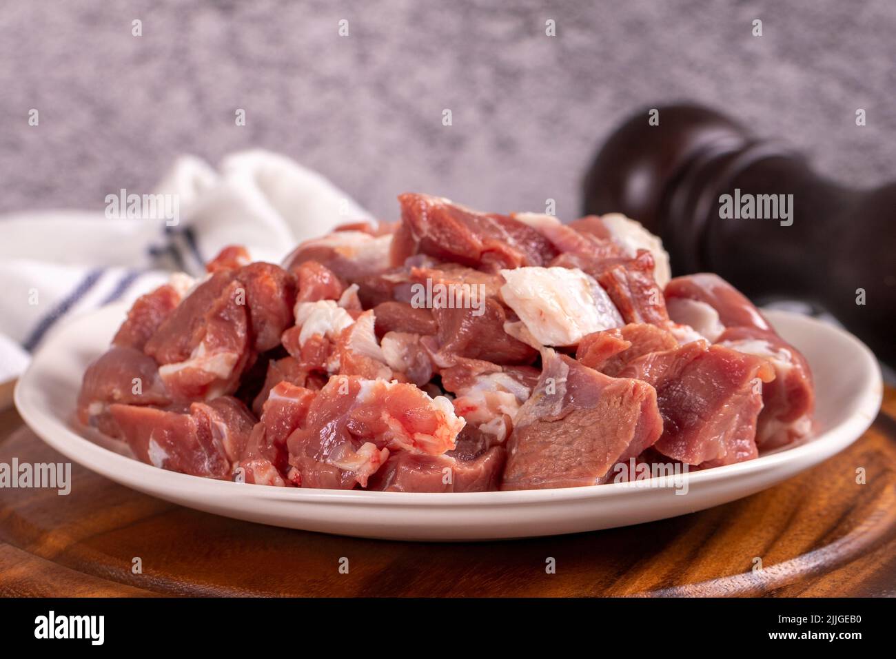 Carne de cordero en cubitos. Carne roja picada en un plato sobre un suelo de piedra. Productos de carnicero. Primer plano Foto de stock