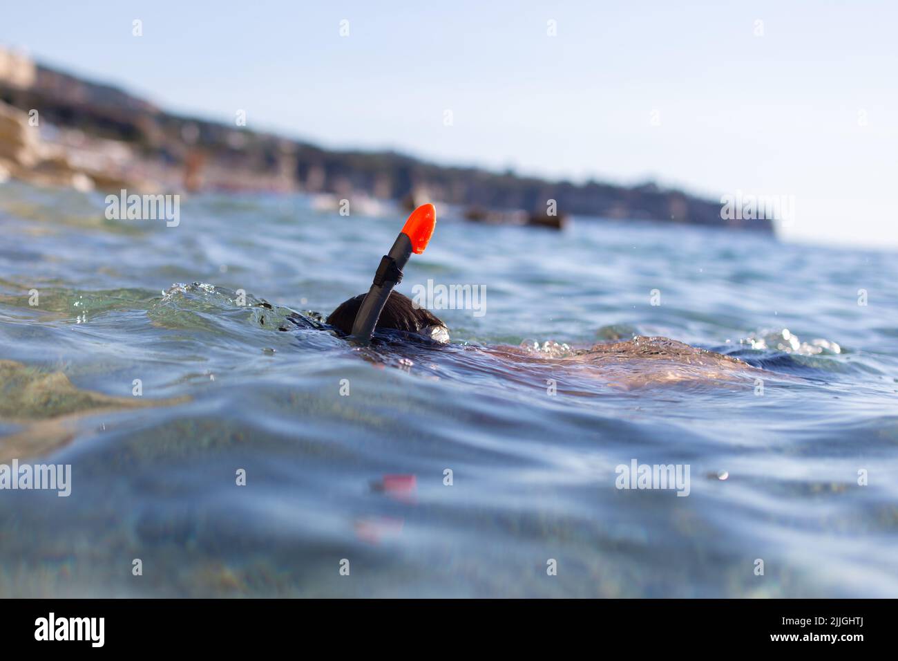 Niño en gafas y tubo de buceo en el mar en la orilla rocosa Foto de stock